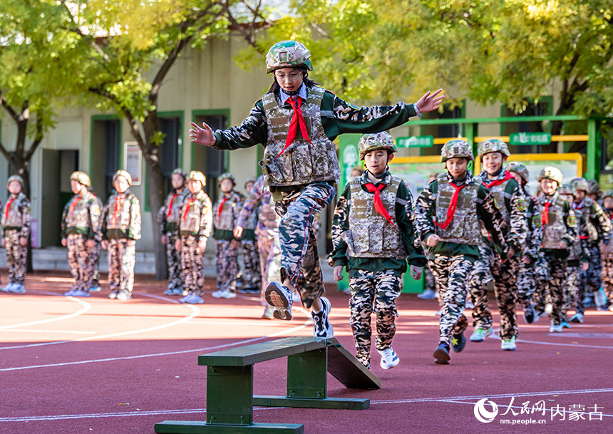 內(nèi)蒙古呼和浩特市玉泉區(qū)五塔寺東街小學(xué)學(xué)生在“心系國防 強國有我”主題教育活動現(xiàn)場參加勇闖獨木橋項目的比拼。丁根厚攝