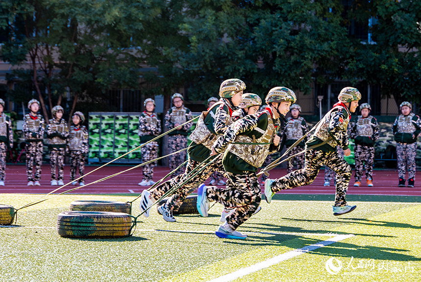內蒙古呼和浩特市玉泉區五塔寺東街小學學生在“心系國防 強國有我”主題教育活動現場參加輪胎拉力賽項目的比拼。丁根厚攝
