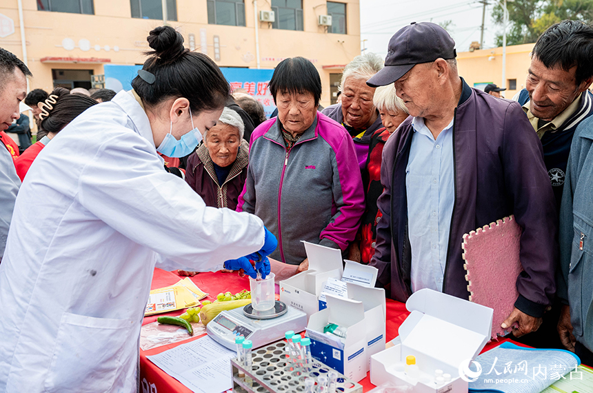 呼和浩特市玉泉區“中國農民豐收節”活動現場，工作人員向村民展示農產品質量安全快速檢測技術。丁根厚攝