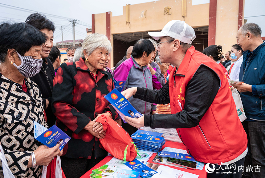 呼和浩特市玉泉區“中國農民豐收節”活動現場,志愿者向村民普及反詐知識。丁根厚攝