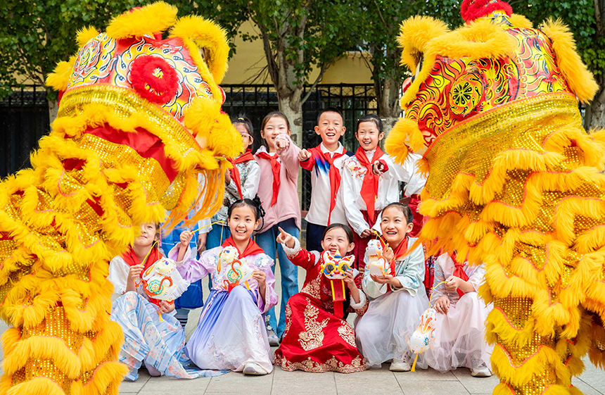 內蒙古呼和浩特市玉泉區清泉街小學表演舞獅的學生在中秋節主題活動上和同學們快樂互動。丁根厚攝