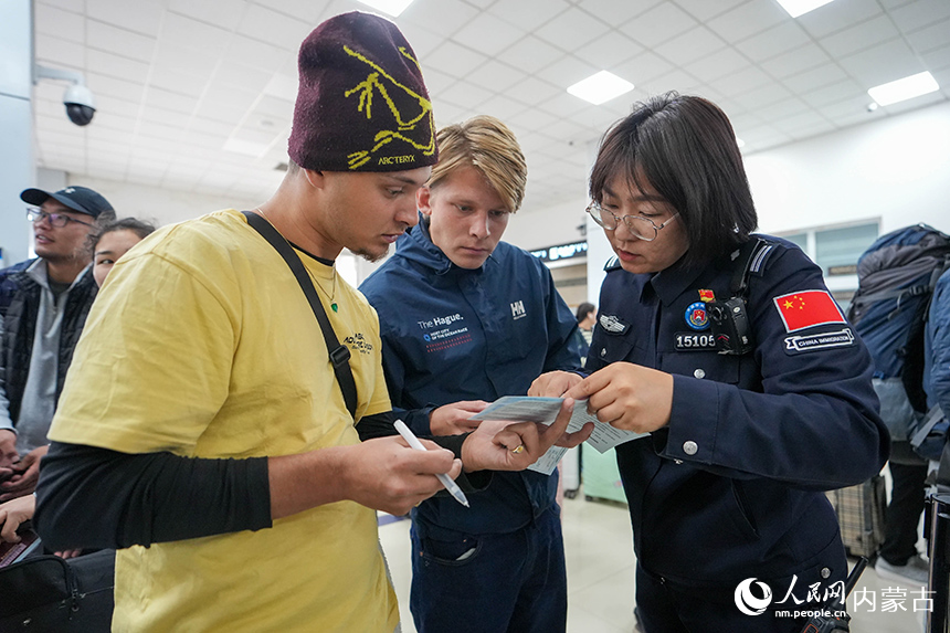 二連出入境邊防檢查站移民管理警察正在為入境旅客提供通關(guān)咨詢。楊金燁攝
