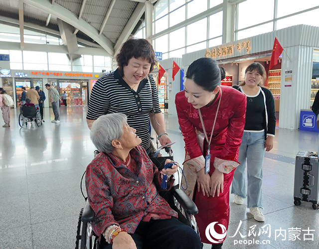 呼和浩特白塔國際機場工作人員為旅客贈送節日出行紀念品。內蒙古自治區交通運輸廳供圖