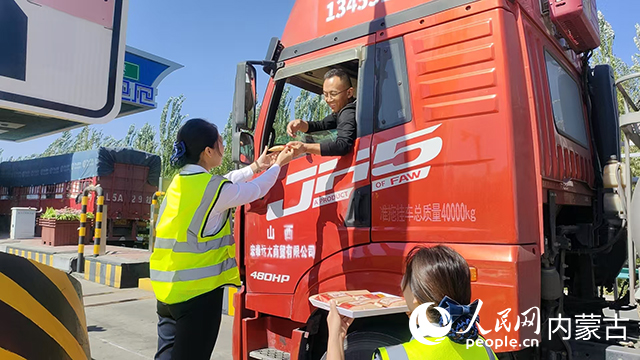 10月6日,內蒙古交通集團巴彥淖爾分公司臨河新區收費所工作人員將月餅送到貨車司機手中。內蒙古自治區交通運輸廳供圖