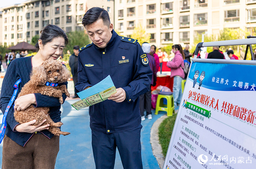 呼和浩特市玉泉區“文明市集”主題活動現場，城管隊員給居民講解文明養犬知識。丁根厚攝