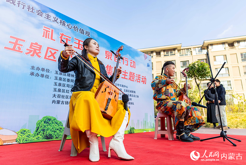 呼和浩特市玉泉區(qū)“文明市集”主題活動現(xiàn)場，烏蘭牧騎隊員在為社區(qū)居民表演馬頭琴演奏。丁根厚攝