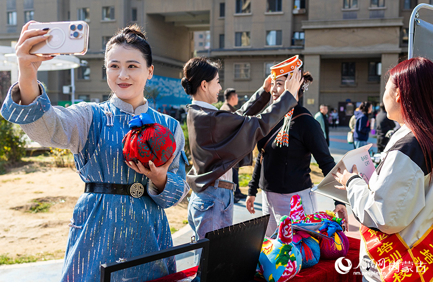 呼和浩特市玉泉區(qū)“文明市集”主題活動(dòng)現(xiàn)場,烏蘭牧騎隊(duì)員在了解“敕勒川巧娘”民族手工藝品。丁根厚攝