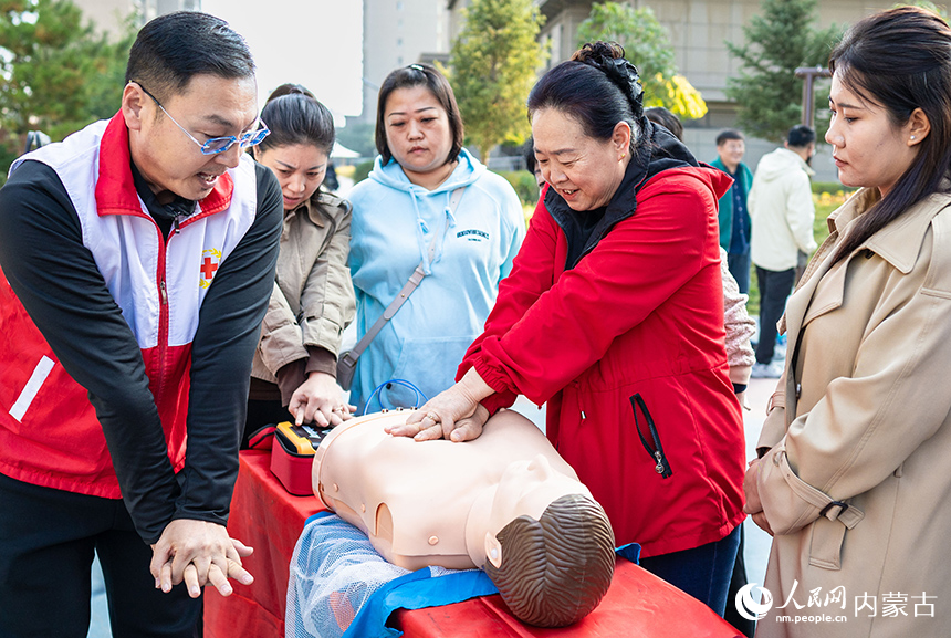 呼和浩特市玉泉區“文明市集”主題活動現場，社區居民在紅十字志愿者指導下學習應急救護技能。丁根厚攝
