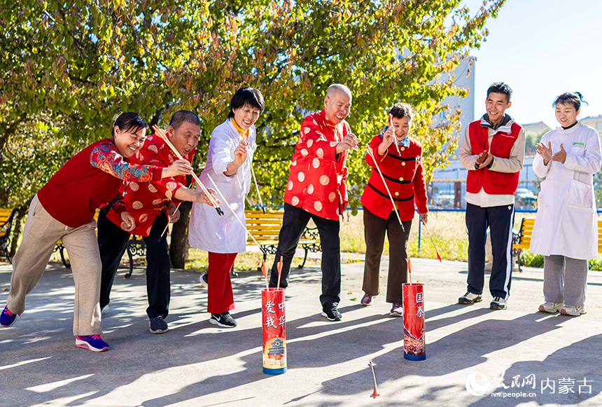 老人們在呼和浩特市玉泉區民政局“愛心敬老 情暖重陽”主題活動現場玩投壺游戲。丁根厚攝