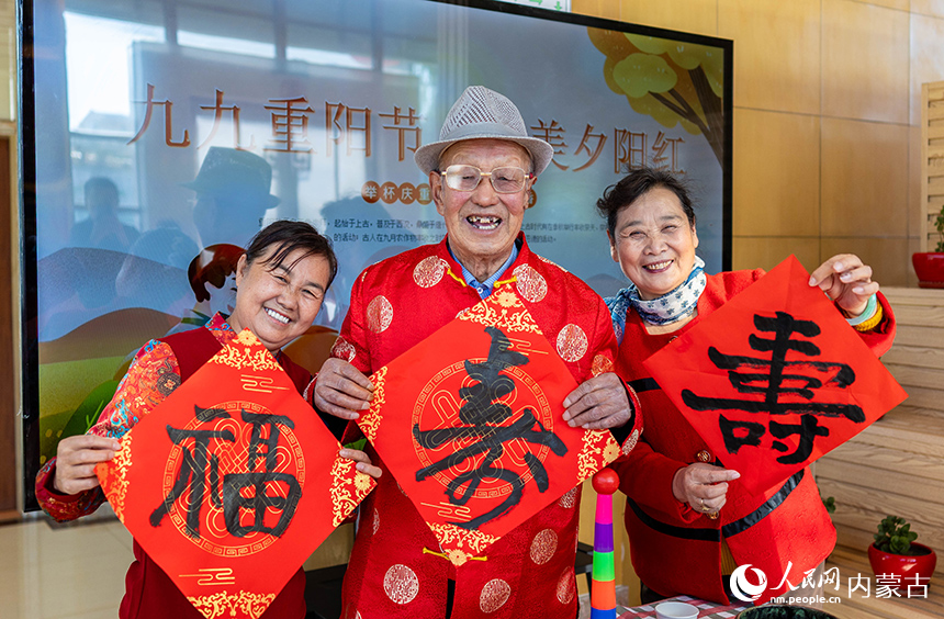 老人們手持“壽”字在呼和浩特市玉泉區民政局“愛心敬老 情暖重陽”主題活動現場留影。丁根厚攝