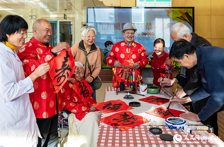 文化志愿者在呼和浩特市玉泉區(qū)民政局“愛心敬老 情暖重陽(yáng)”主題活動(dòng)現(xiàn)場(chǎng)為老人們書寫“壽”字書法作品。丁根厚攝