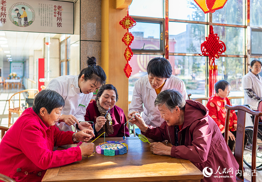 護(hù)理員陪伴老人們在呼和浩特市玉泉區(qū)民政局“愛心敬老 情暖重陽”主題活動現(xiàn)場玩益智游戲。丁根厚攝