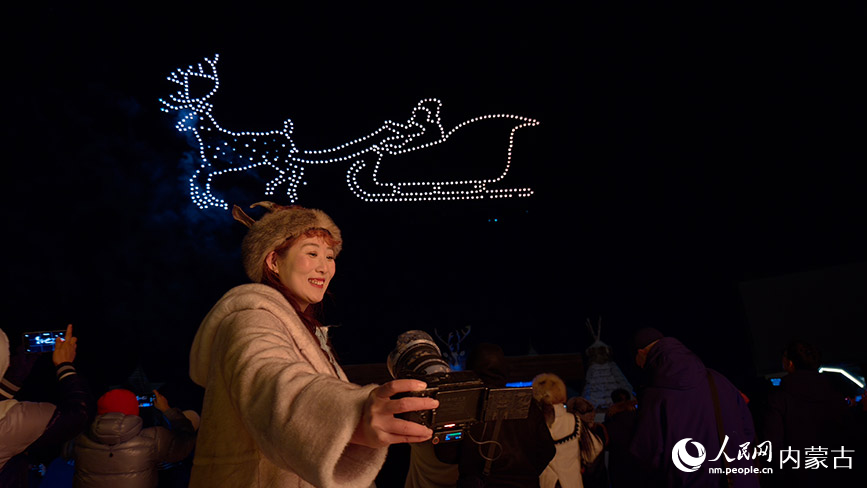 11月6日,呼倫貝爾市根河市的敖魯古雅廣場,游客在無人機(jī)表演現(xiàn)場拍照留念。人民網(wǎng)記者 張力洋攝
