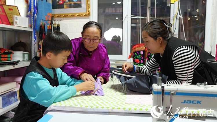 71歲的薩仁格樂正教著她的女兒和外孫做蒙古靴刺繡。蘇米雅攝