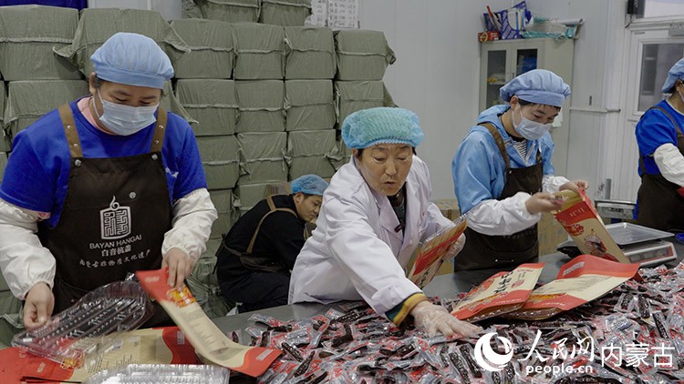 白秀枝在非遺工坊的包裝車間和工人一起包裝牛肉干。李旭明 攝