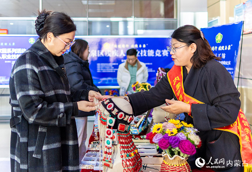 11月16日，呼和浩特市玉泉區(qū)殘疾人職業(yè)技能競(jìng)賽現(xiàn)場(chǎng)，市民在殘疾人就業(yè)成果展示區(qū)了解一款“敕勒川巧娘”手工藝品。丁根厚攝