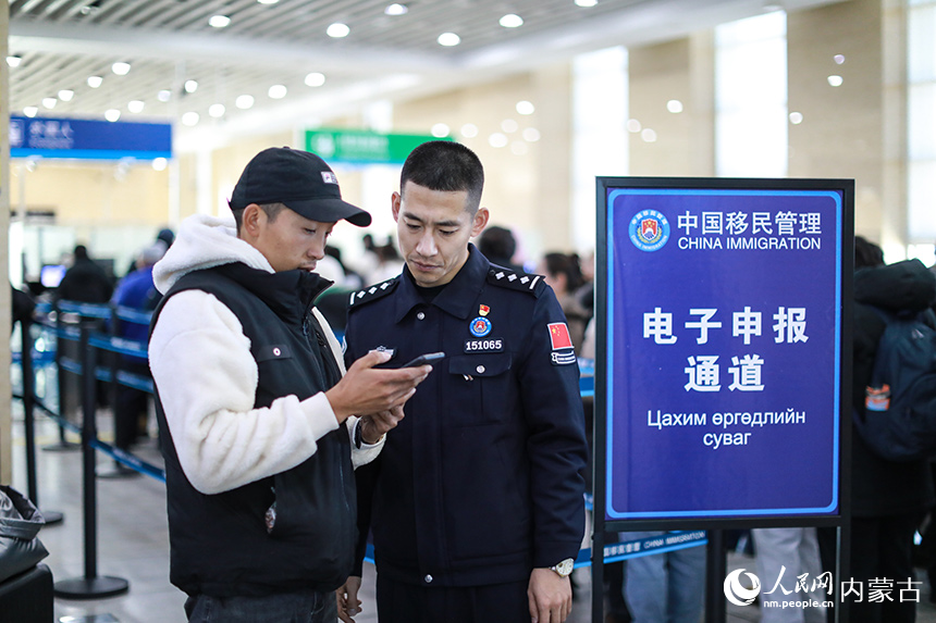 二連出入境邊防檢查站移民管理警察協(xié)助蒙古國(guó)旅客網(wǎng)上填報(bào)外國(guó)人入境卡。郭鵬杰攝