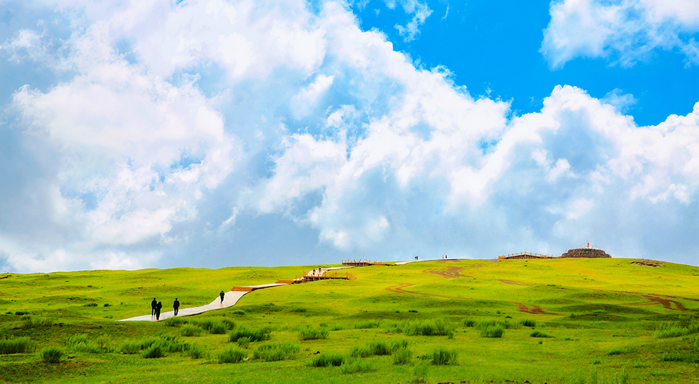 登頂淖爾梁，遠山疊翠銜著流云，腳下草甸綿延至天際。