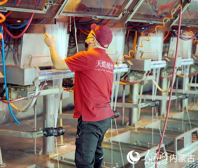 內蒙古天皓玻纖有限責任公司拉絲車間工人正在工作。人民網記者 齊浩男攝