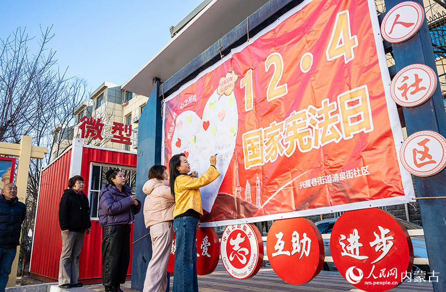 12月4日，呼和浩特市玉泉區清泉街社區居民在“國家憲法日”主題宣傳展板上簽名。丁根厚攝