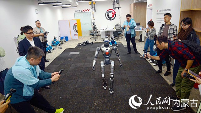 在深圳眾擎機器人公司,機器人現(xiàn)場演示格斗技巧,記者駐足記錄。人民網(wǎng)記者 張力洋攝