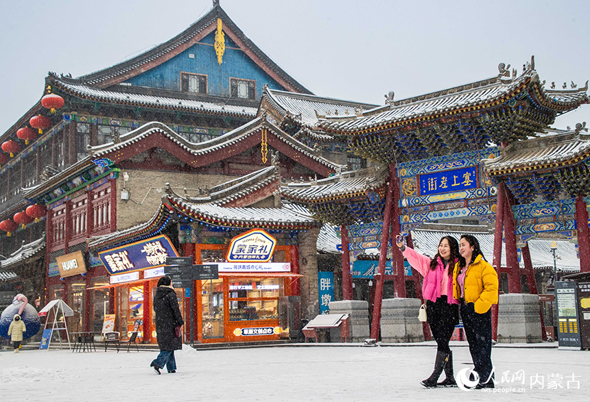 游人在呼和浩特市玉泉區(qū)塞上老街旅游休閑街區(qū)賞雪拍照。丁根厚攝